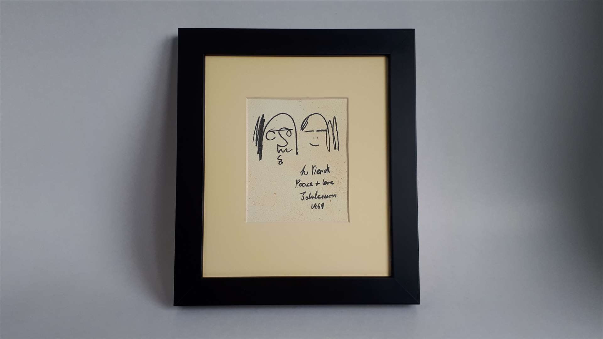 The framed picture is a sketch of Lennon and Yoko Ono in John Lennon’s characteristic caricature style.