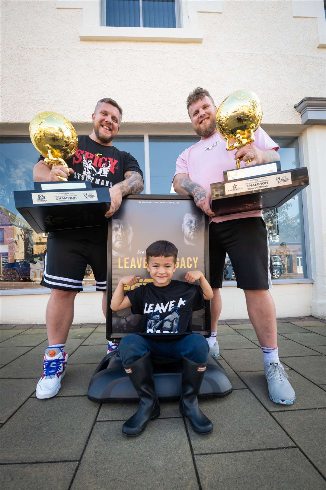 Luke and Tom Stoltman with Jayden Timoney outside the shop. Picture: Callum Mackay..