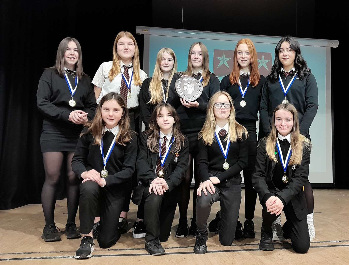 The winning team show off their medals and trophy at a school assembly on Monday.