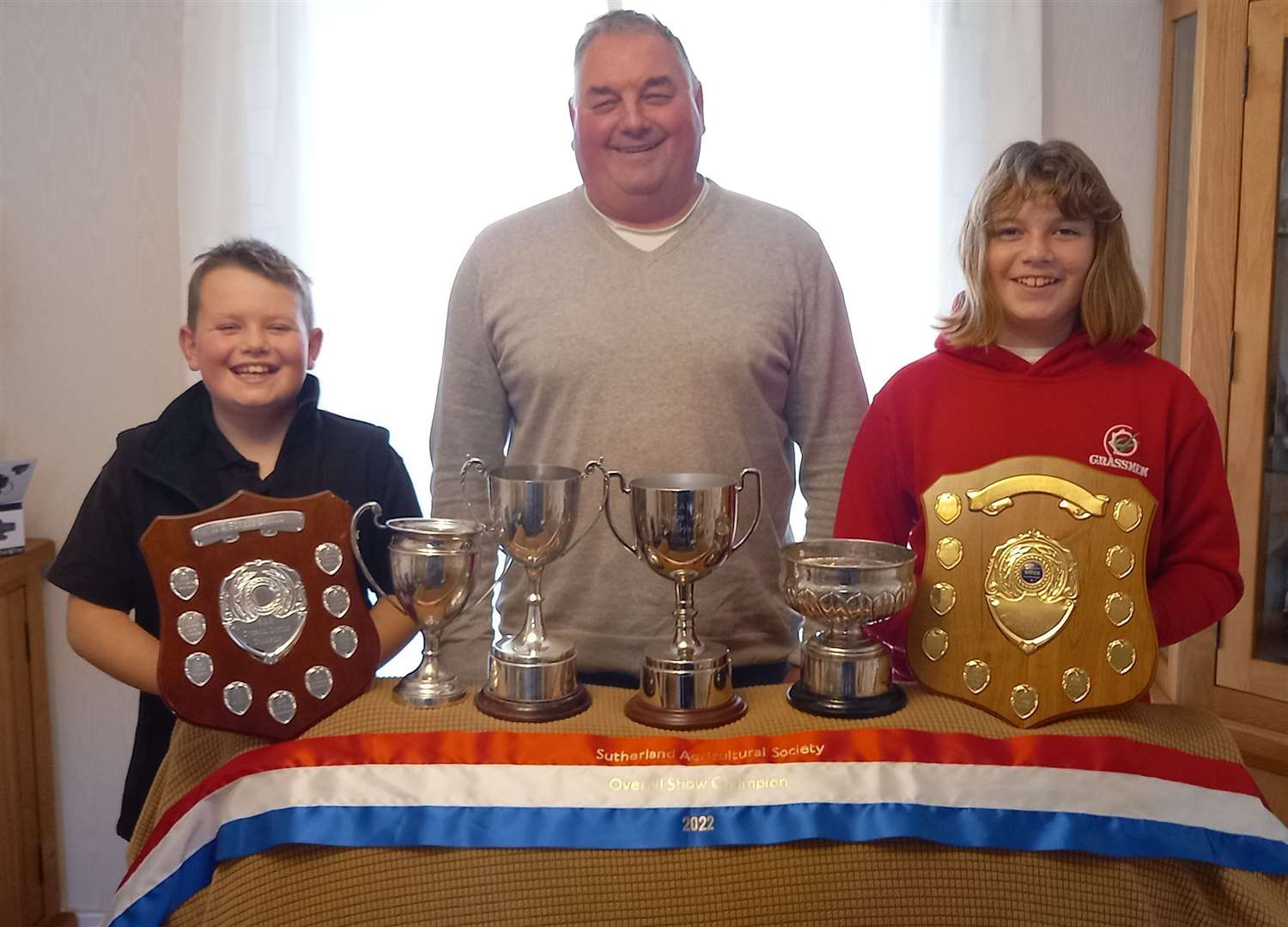 Crofter John Smith, with his son Kyle and daughter Katie, shows off some of the trophies he won this year.