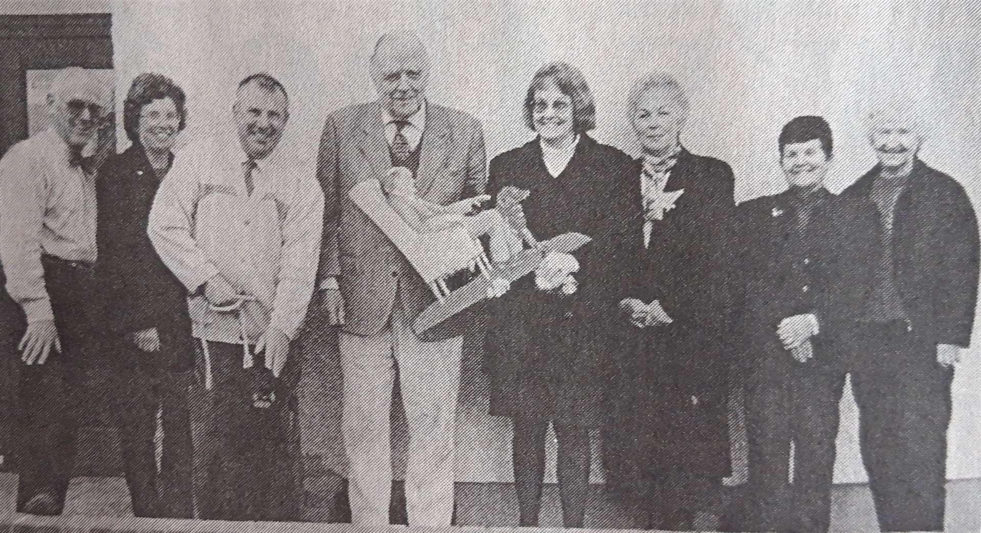 Committee joint secretary Agnes Calder presents the weather vane to Col. Sir Allan Gilmour, in the company of fellow members, from left, Russell Taylor, Christine Milne, Stuart Milne with Toddy the dog, Phyllis Ross, Alice Grant and Janet Maclean.