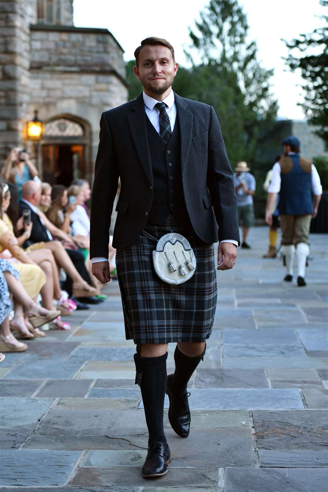 Adam Gray on the runway at Dressed to Kilt sporting a Glen Orchy tweed jacket and waistcoat in Oban Mist tartan supplied by MacGregor and MacDuff.
