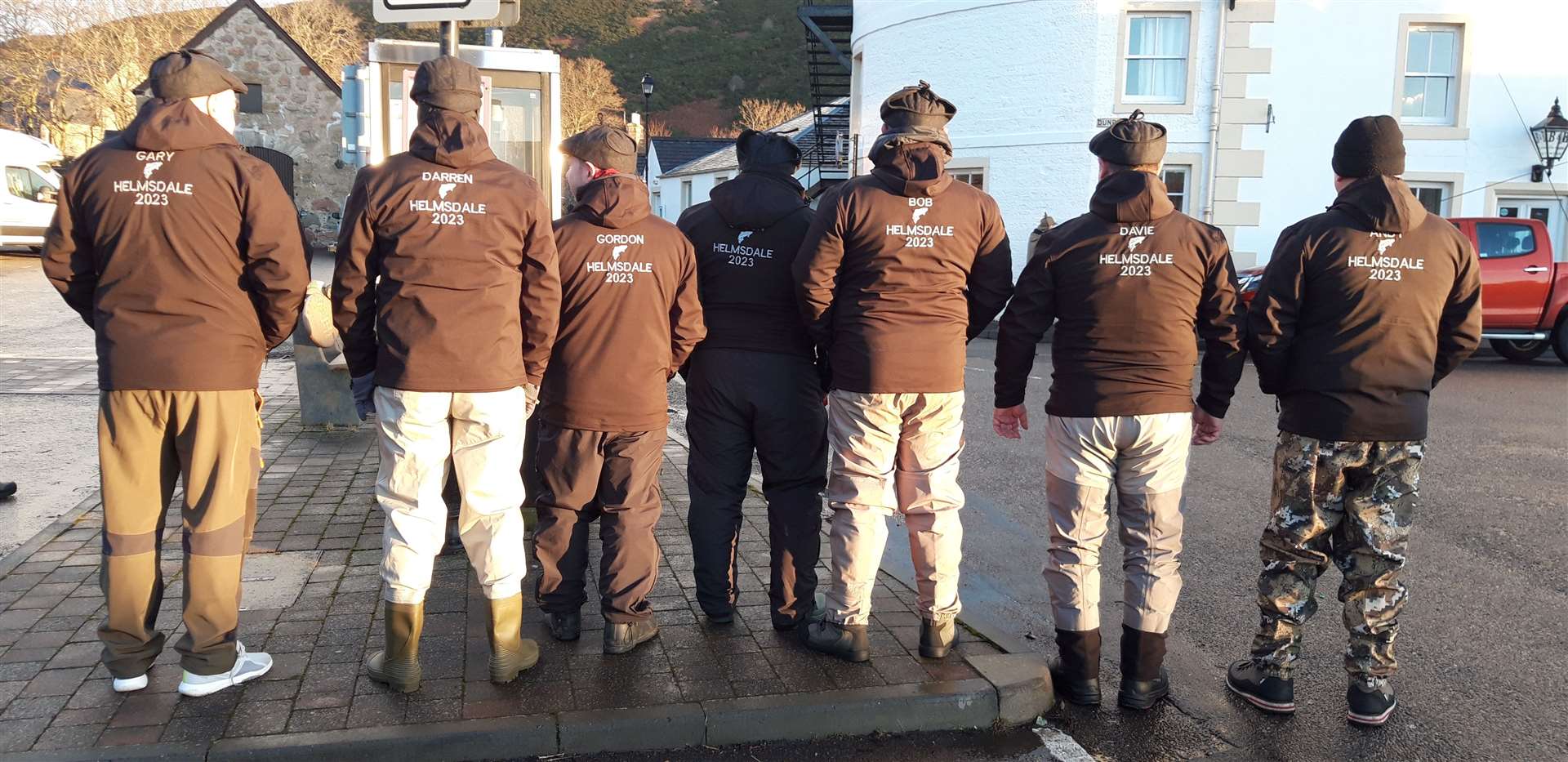 The friends show off the wording on the back of their matching jackets – 'Helmsdale 2023'.