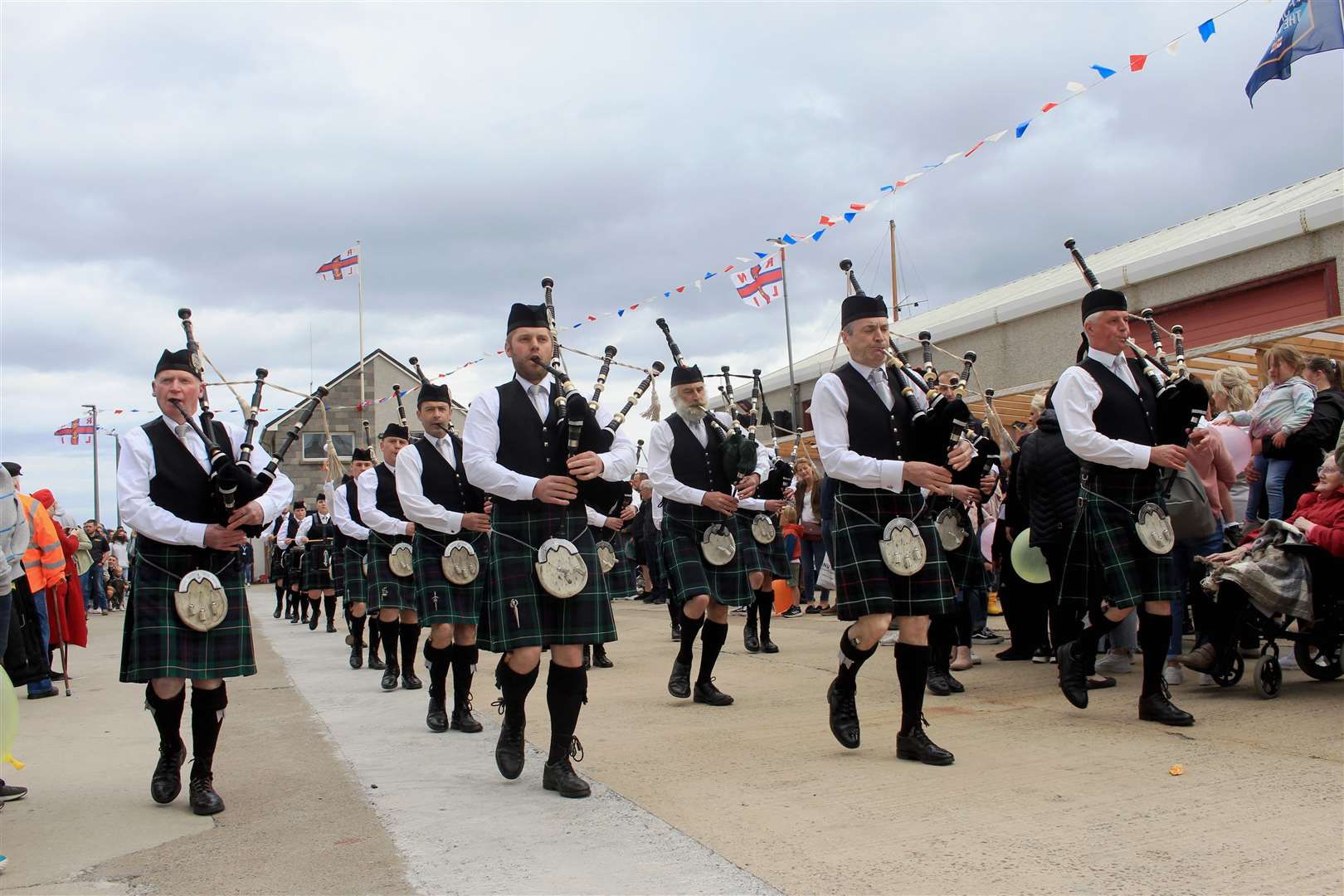Wick RBLS Pipe Band marching along the quayside with the lifeboat station in the background. Picture: Alan Hendry