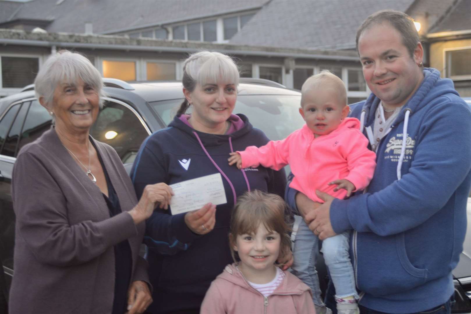 Joan Mackay who compiled the clues and set out the route for the car treasure hunt hands over the top prize to the Macleod family from Strathy. Picture: Jim A Johnston