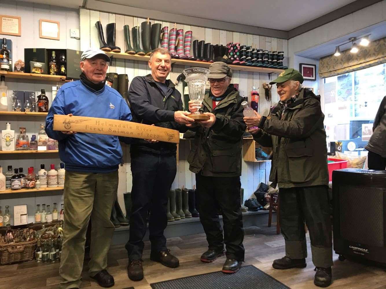 Addie Sutherland is presented with the crystal vase by Andy Sutherland, who caught the first fish in 2019, while Johnny Sutherland (left) holds the whisky stave. Standing right with the bottle of gin is Sonny Jappy, whose grandson Findlay Adams made the first cast this year.