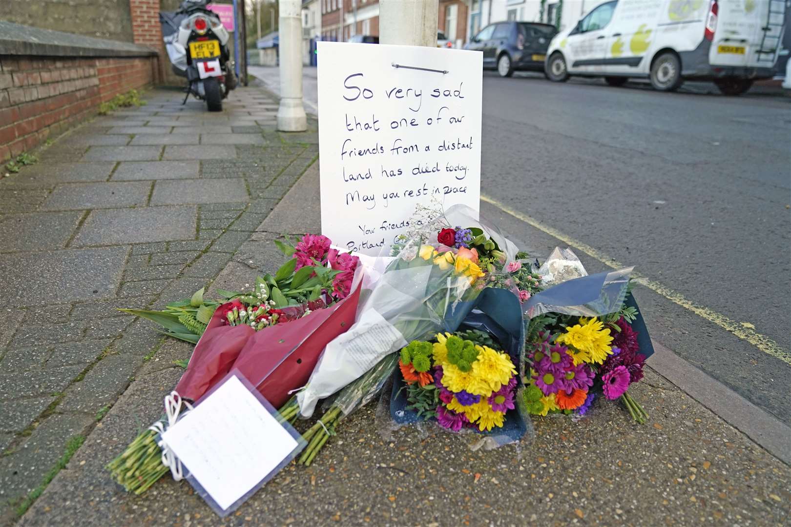 Flowers were left at the entrance at Portland Port in Dorset, following the death of the asylum seeker aboard the barge last month (Andrew Matthews/PA)