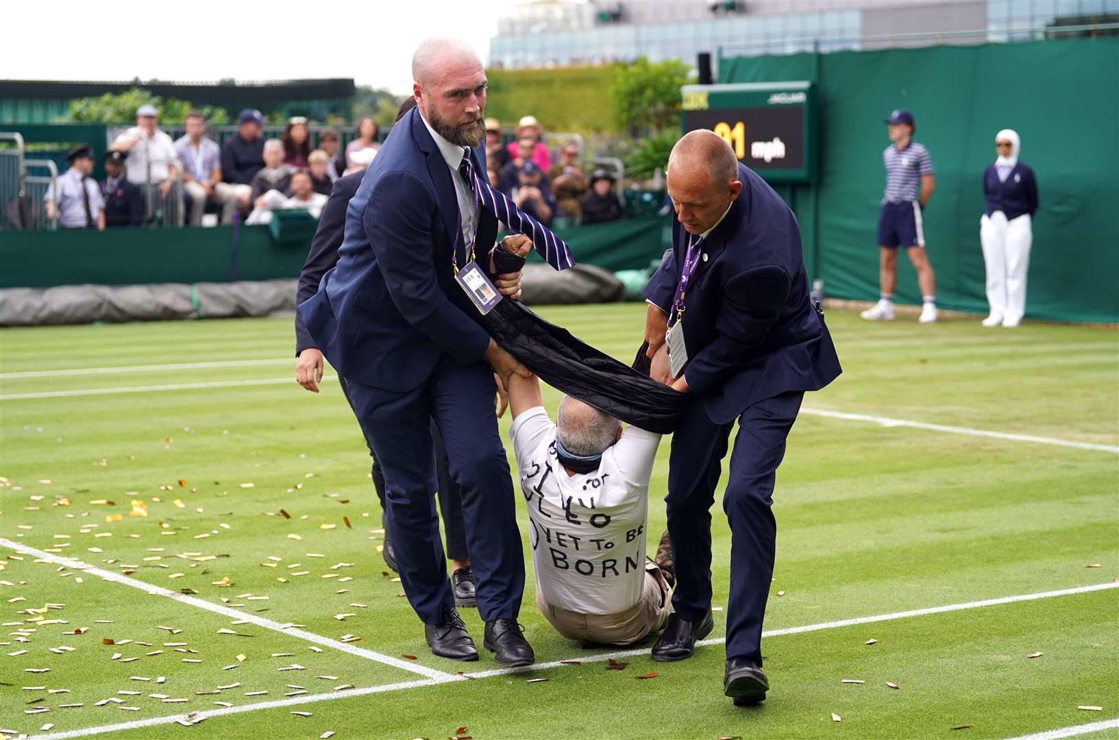A Just Stop Oil protester is carried off court 18 after throwing confetti on to the grass during a match on day three of the 2023 Wimbledon Championships (Adam Davy/PA)