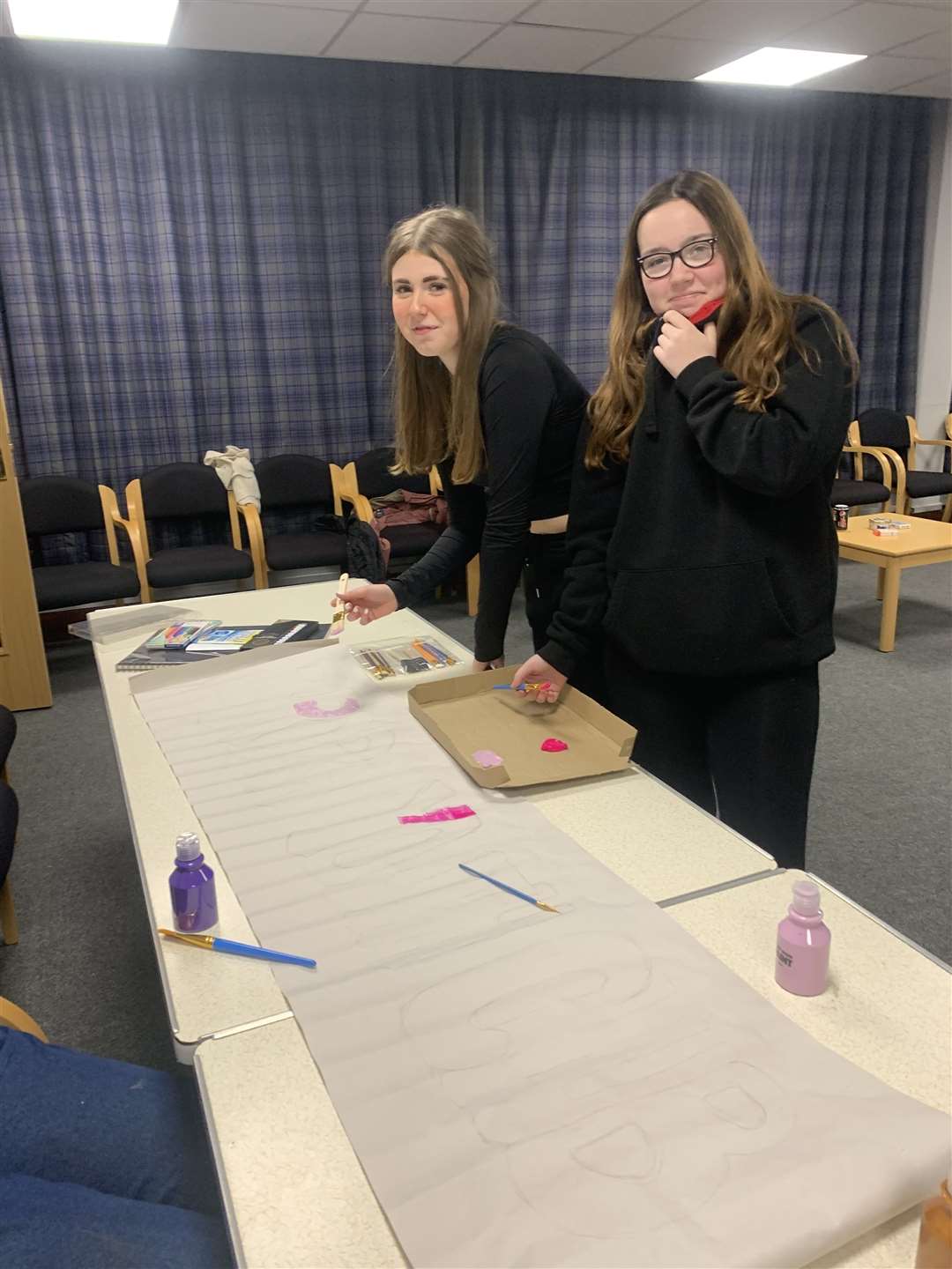 Rebecca Prowse and Grace Dent begin painting a banner for the youth club.