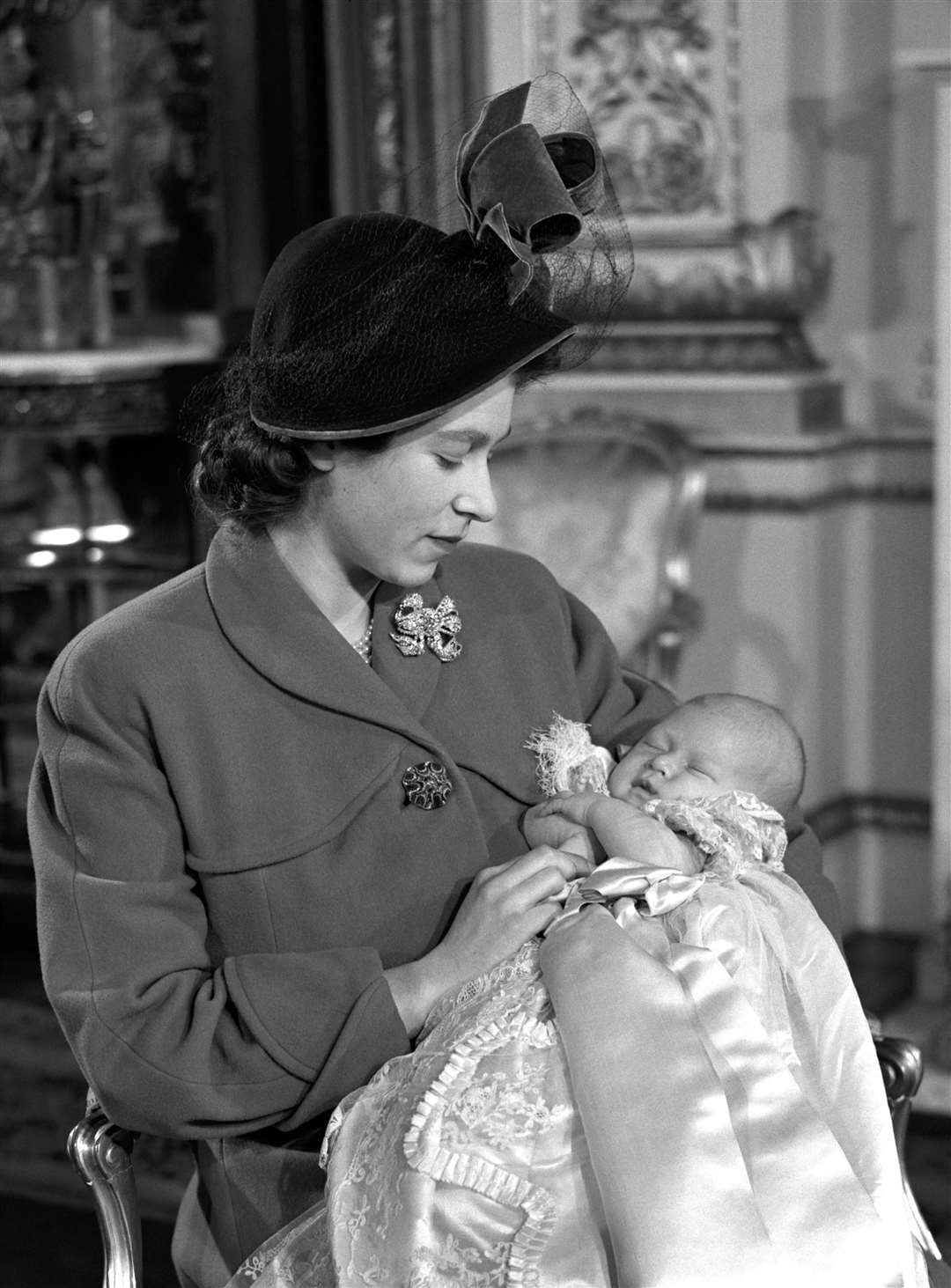Princess Elizabeth (later Queen Elizabeth II) holding her son Prince Charles after his christening ceremony in Buckingham Palace.