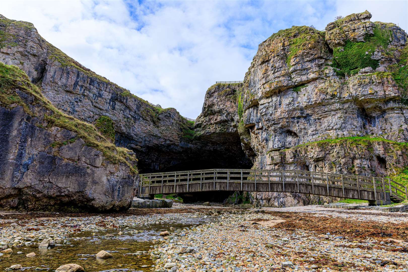 The entrance and the bridge over the stream at Smoo Cave. Smoo Cave is a combined coastal and freshwater cave in Durness, Sutherland, Scotland, UK