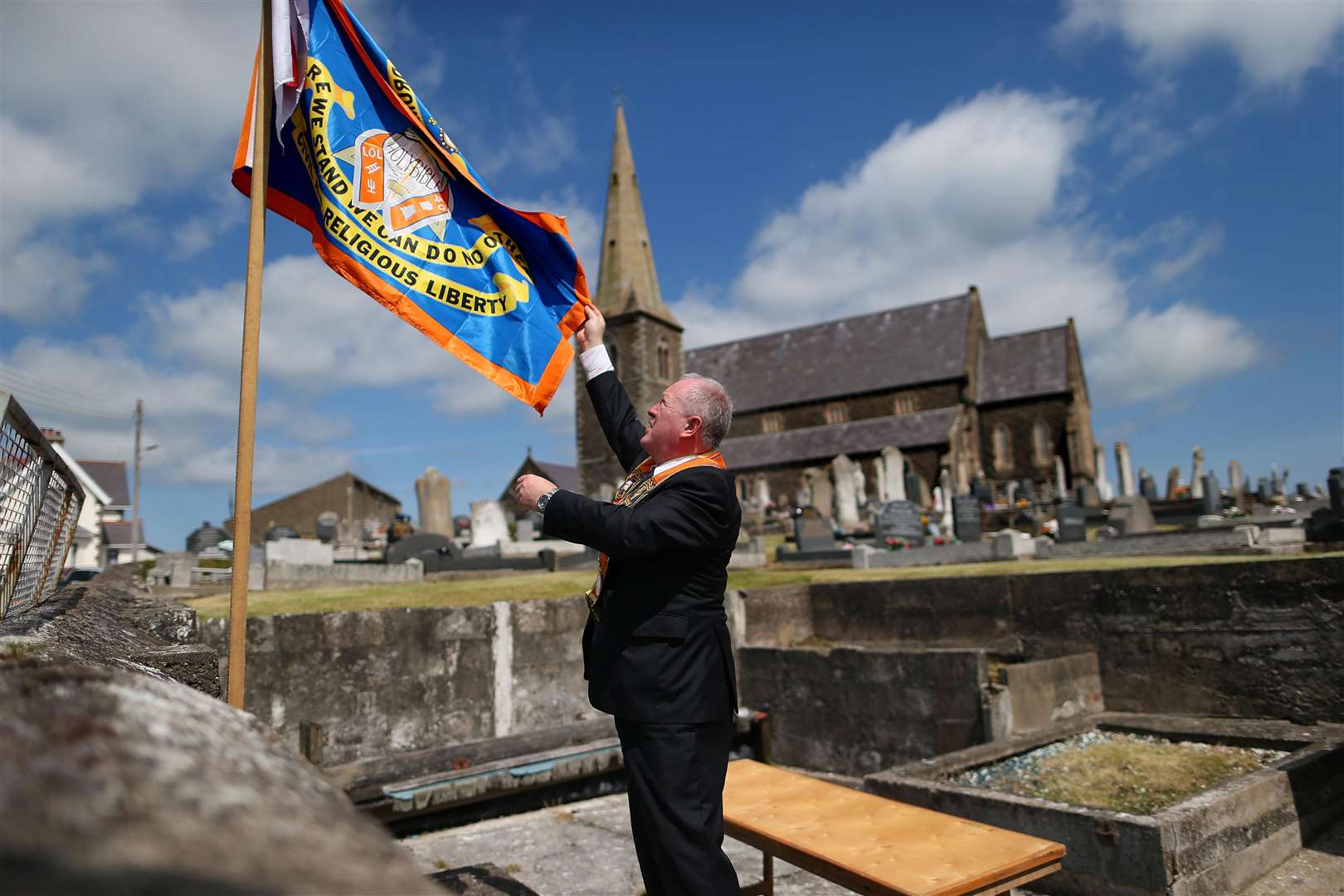 An Orange Order member hanging a Drumcree protest flag outside Drumcree Church in Portadown (Julien Behal/PA)