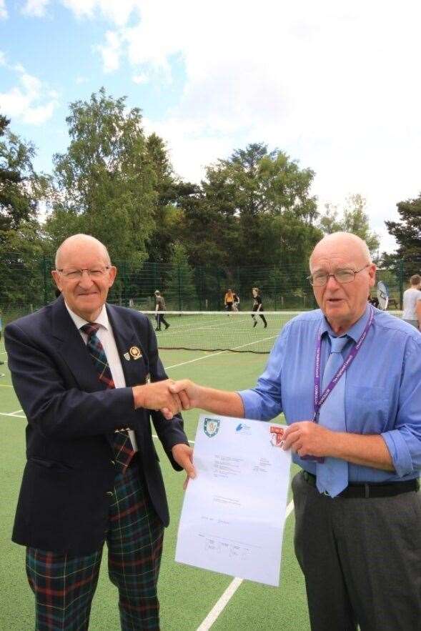 Cllr Jim McGillivray, right, and Willie Mackay shake hands while holding up the MUGA’s official certificate of completion.
