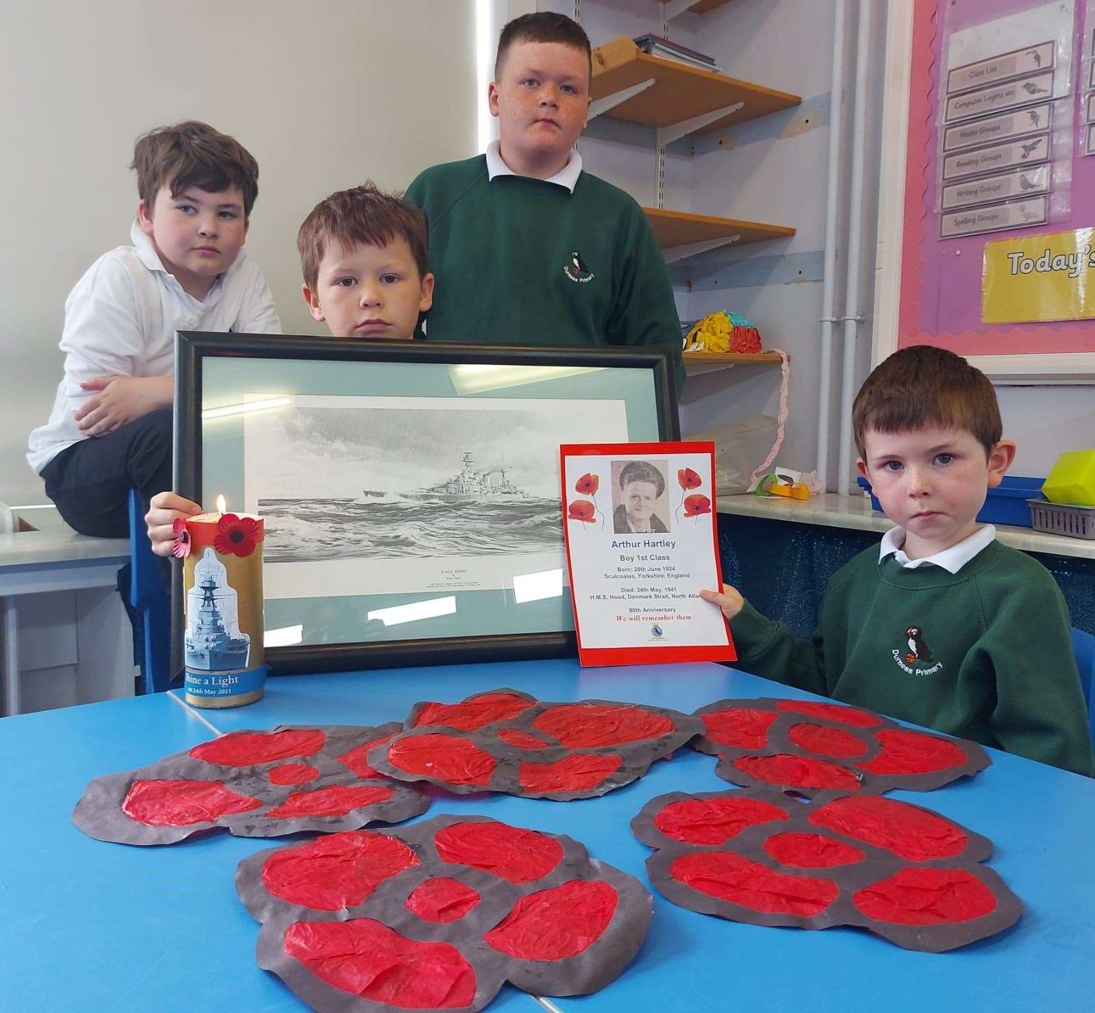 Durness Primary School pupils with a picture of HMS Hood and the poster they created to honour the youngest crew member.