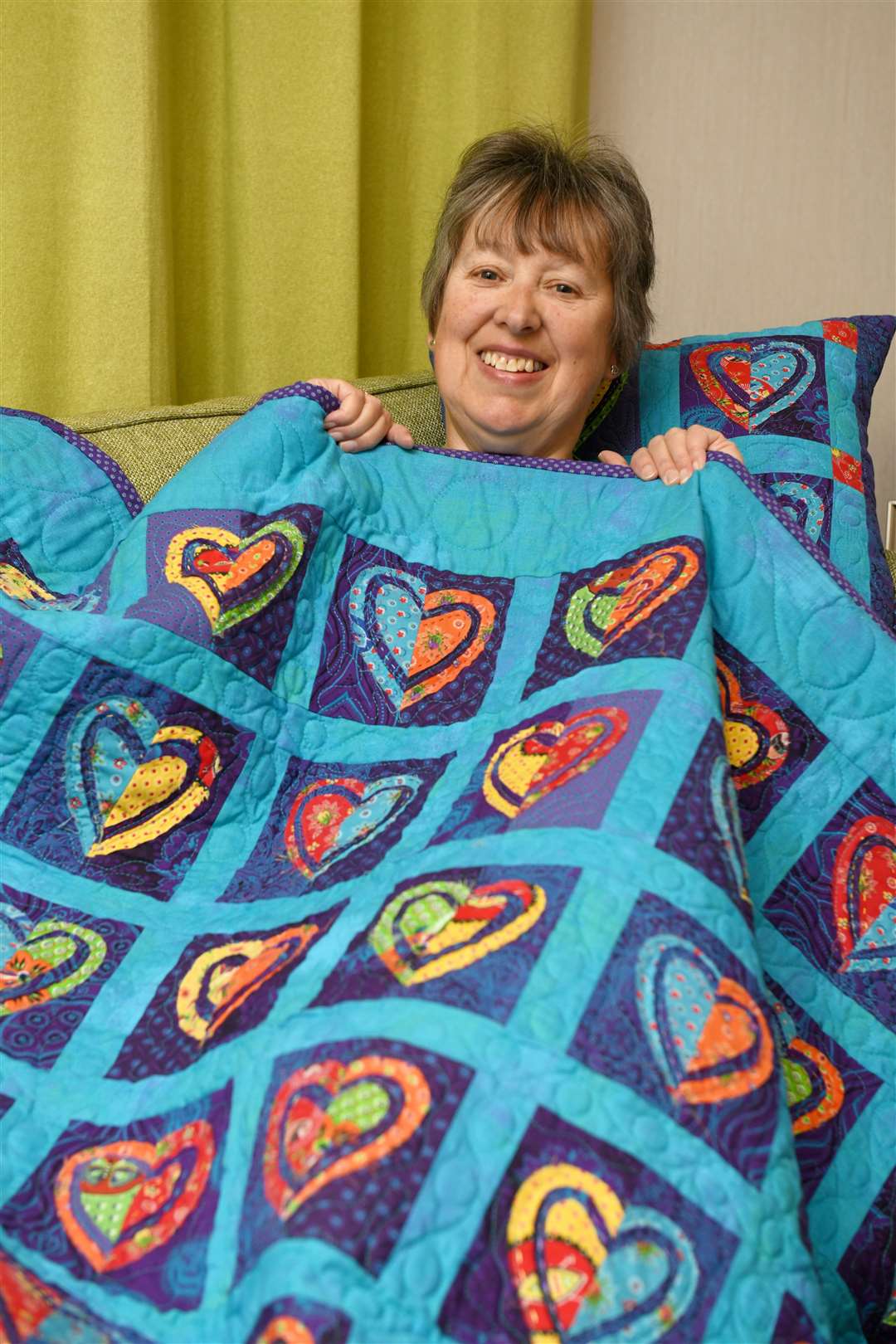 Shona Docherty, Macmillan Cancer Support Easter Ross fundraising committee chair showing off the cushions and the quilt inspired by Gill Thompson. Picture: James Mackenzie.