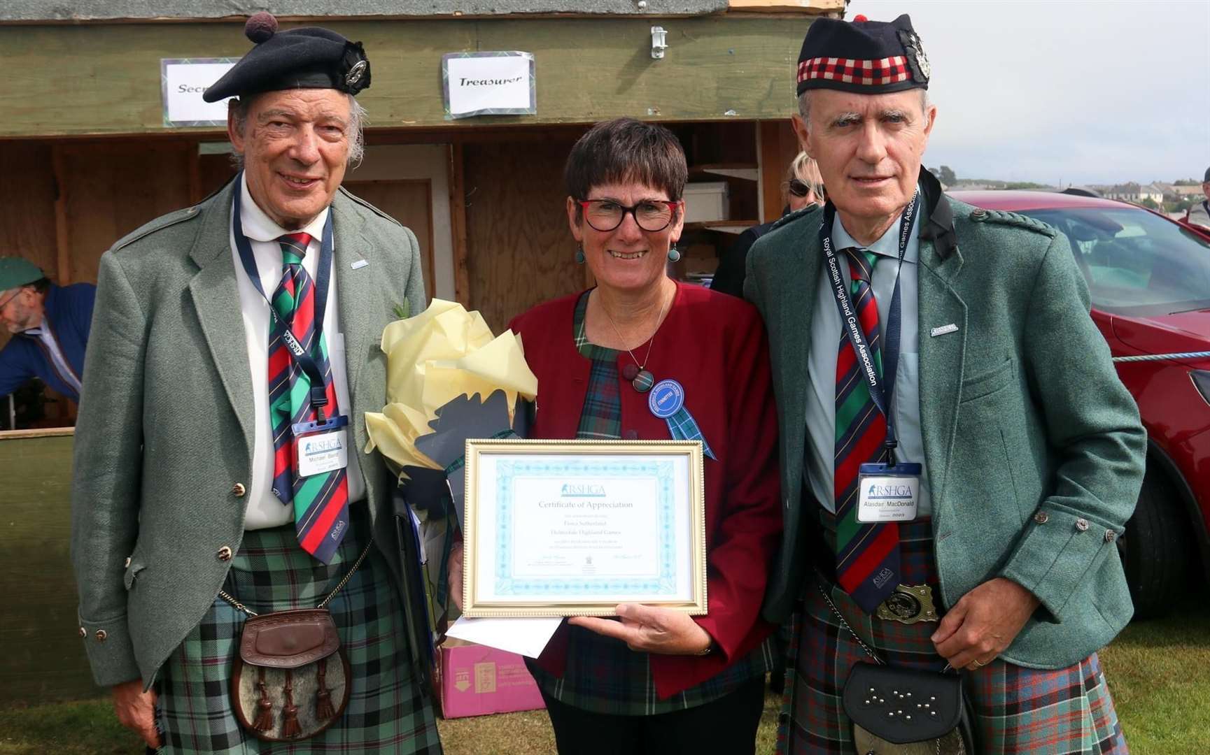 Fiona Sutherland receives her Certificate of Appreciation Award for outstanding long service to the Highland Games. From Michael Baird and Alistair Macdonald, both of the Royal Society Highland Games Association (RSHGA).