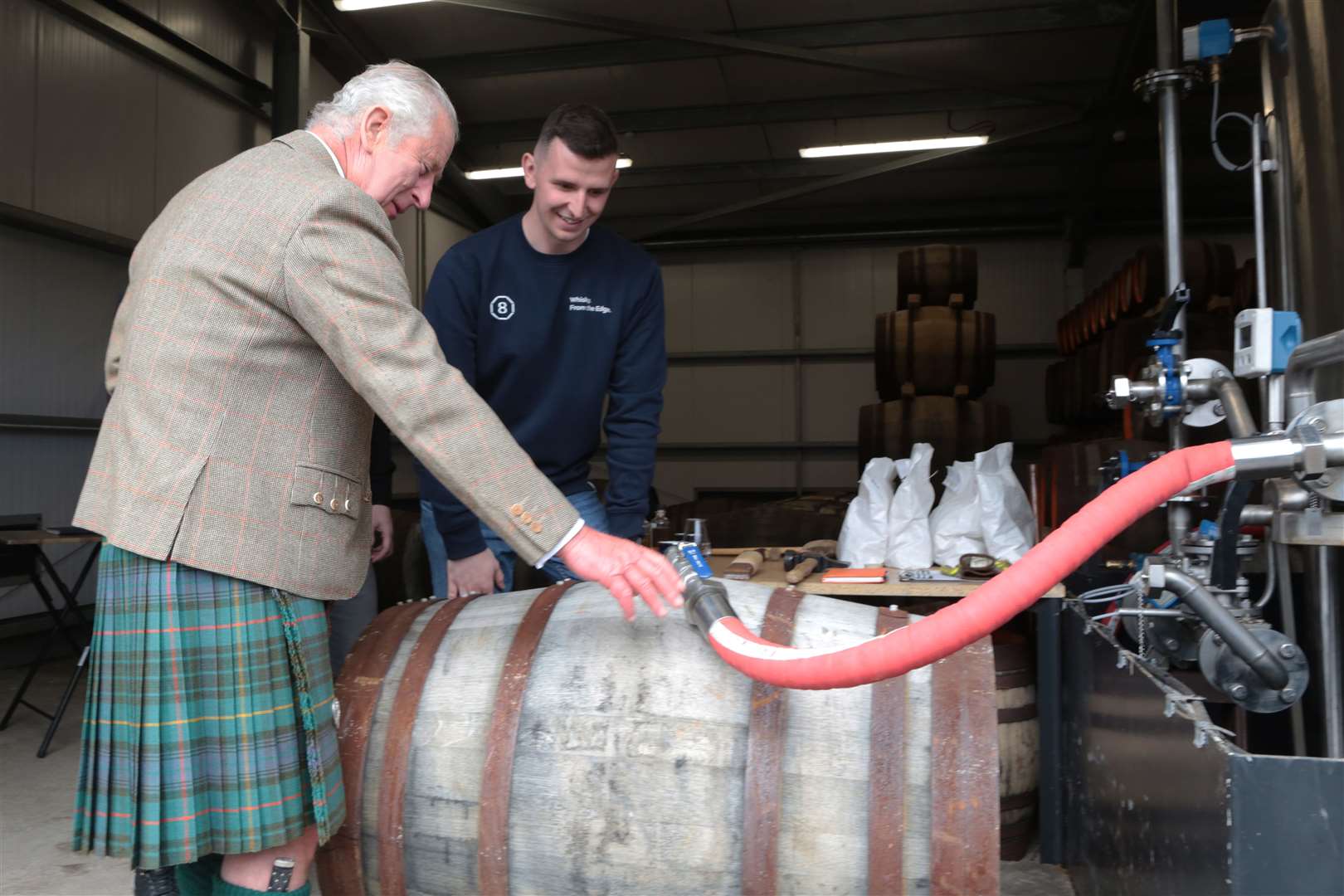 Distillery manager Ryan Sutherland helps the King to fill a cask. Picture: PA