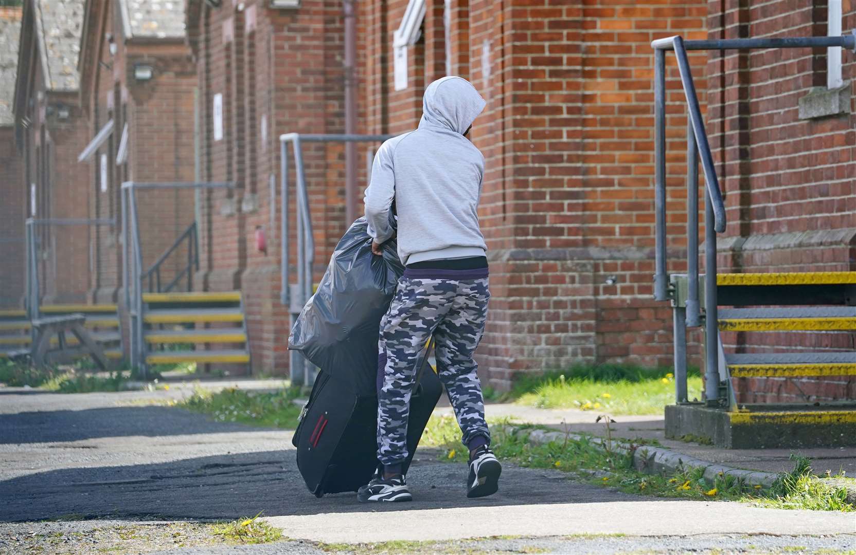 A man thought to be a migrant moves his belongings while he is housed at Napier Barracks in Folkestone, Kent (Gareth Fuller/PA)