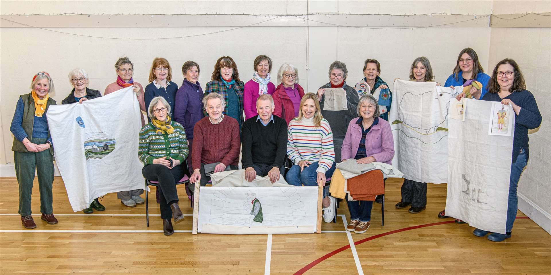 Councillor Richard Gale (centre) is seated between Andrew Crummy and Kirstie Campbell while community stitchers from the Helmsdale area look on. Picture: Angus Mackay Photography