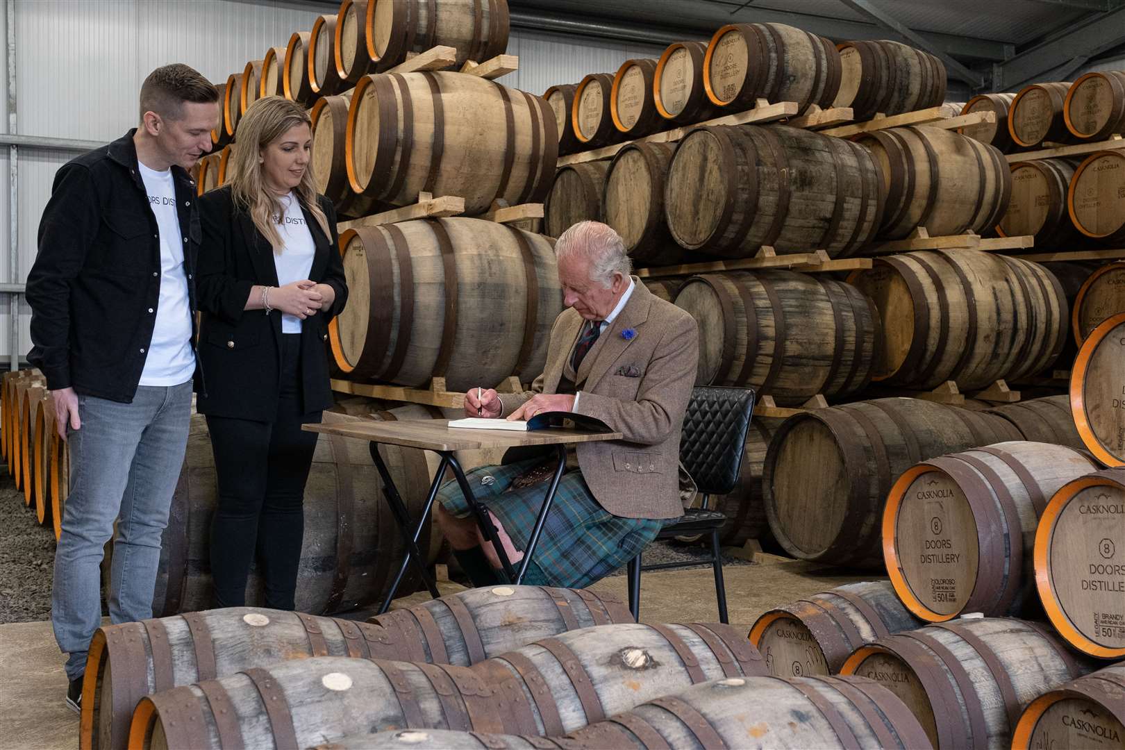 The King signing the visitors' book in the warehouse at 8 Doors Distillery. Picture: Susie Mackenzie