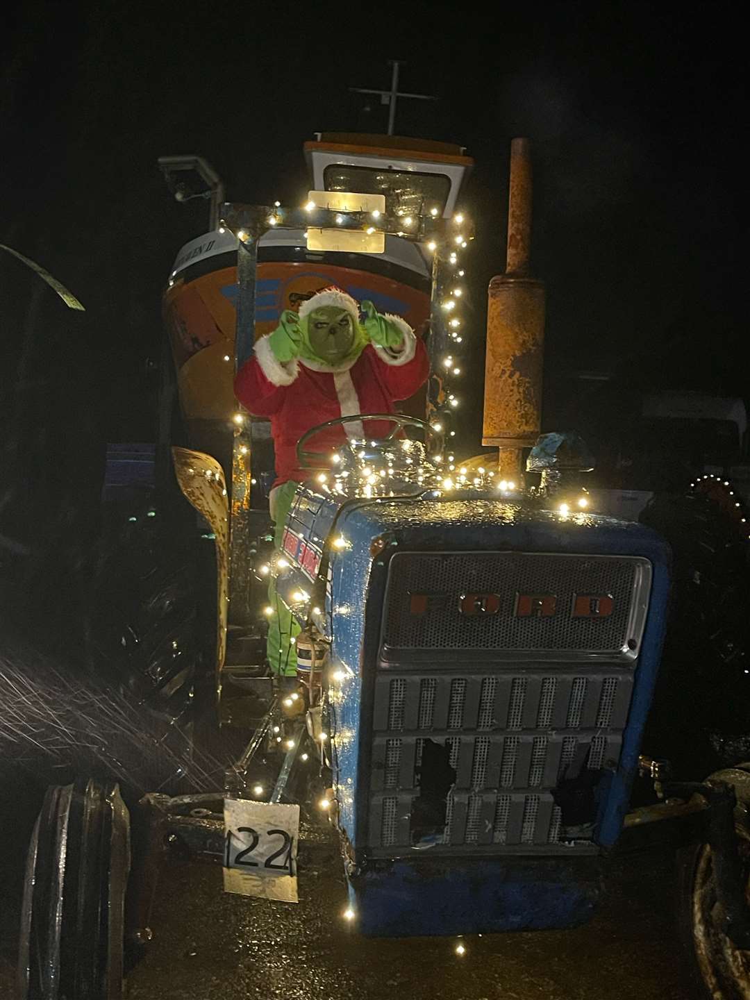 The Grinch at the wheel of a decorated tractor.