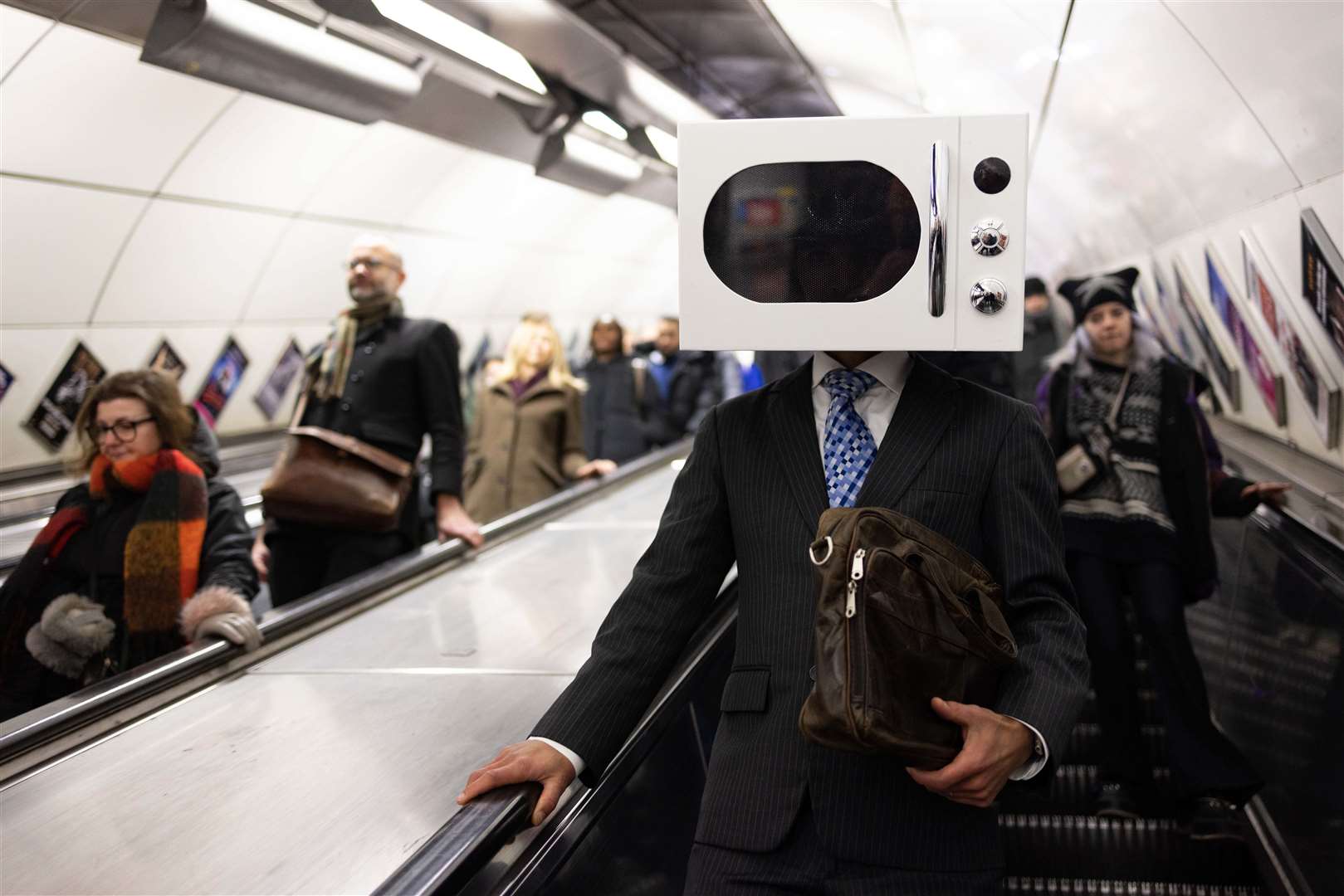 A man on the underground in London with a microwave on his head (David Parry/PA)