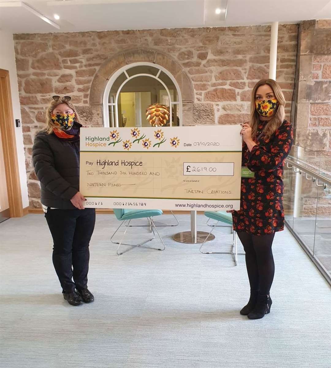 Yvonne Macrae hands her face covering cheque to Emma Nicol of Highland Hospice.