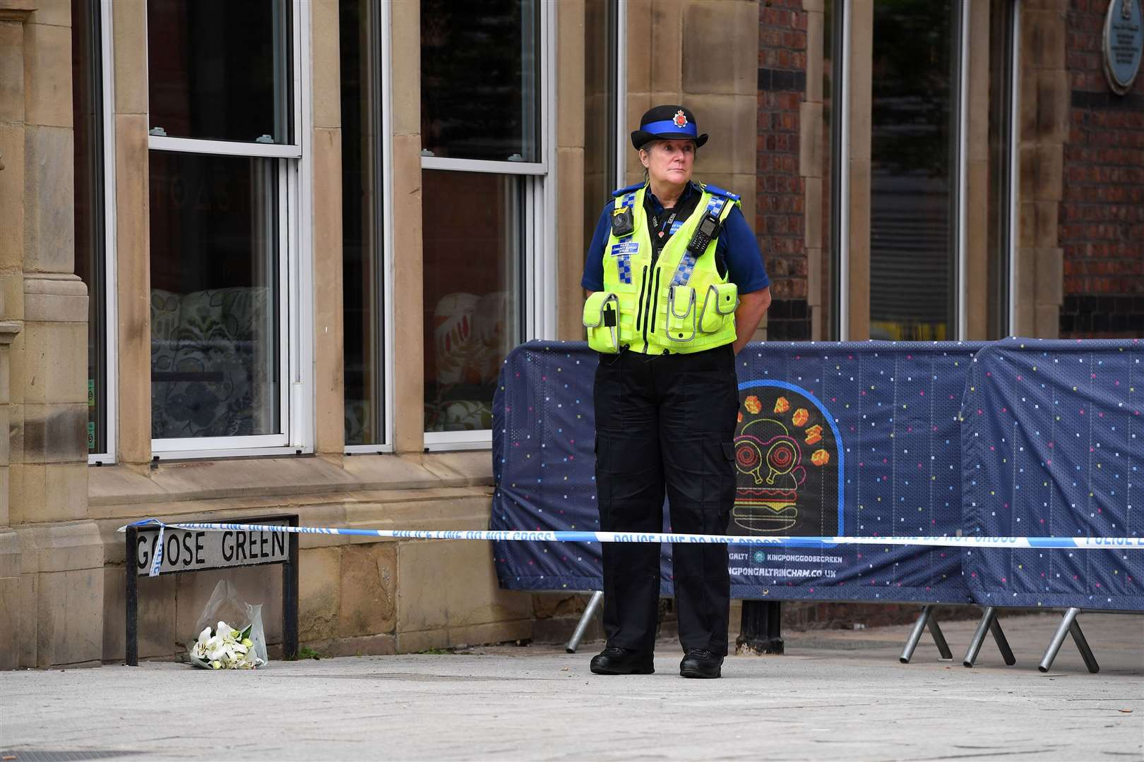 A PCSO stands alongside a floral tribute at the scene in Railway Street in the Goose Green area of Altrincham (Eddie Garvey/PA)