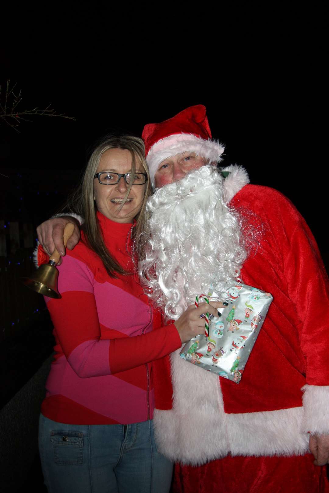 Ashley Poole clutches her beautifully wrapped gift and a candy cane as she poses with Santa for the camera.