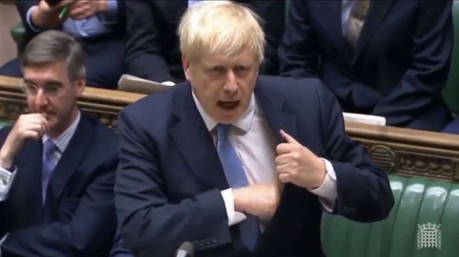 Boris slips his pen into his left hand inside jacket pocket.