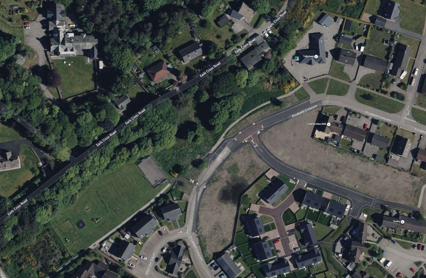 The grey rectangle in this image is the outdoor basketball court and the area of land identified for the building plots is the tree covered land running to the right of it.