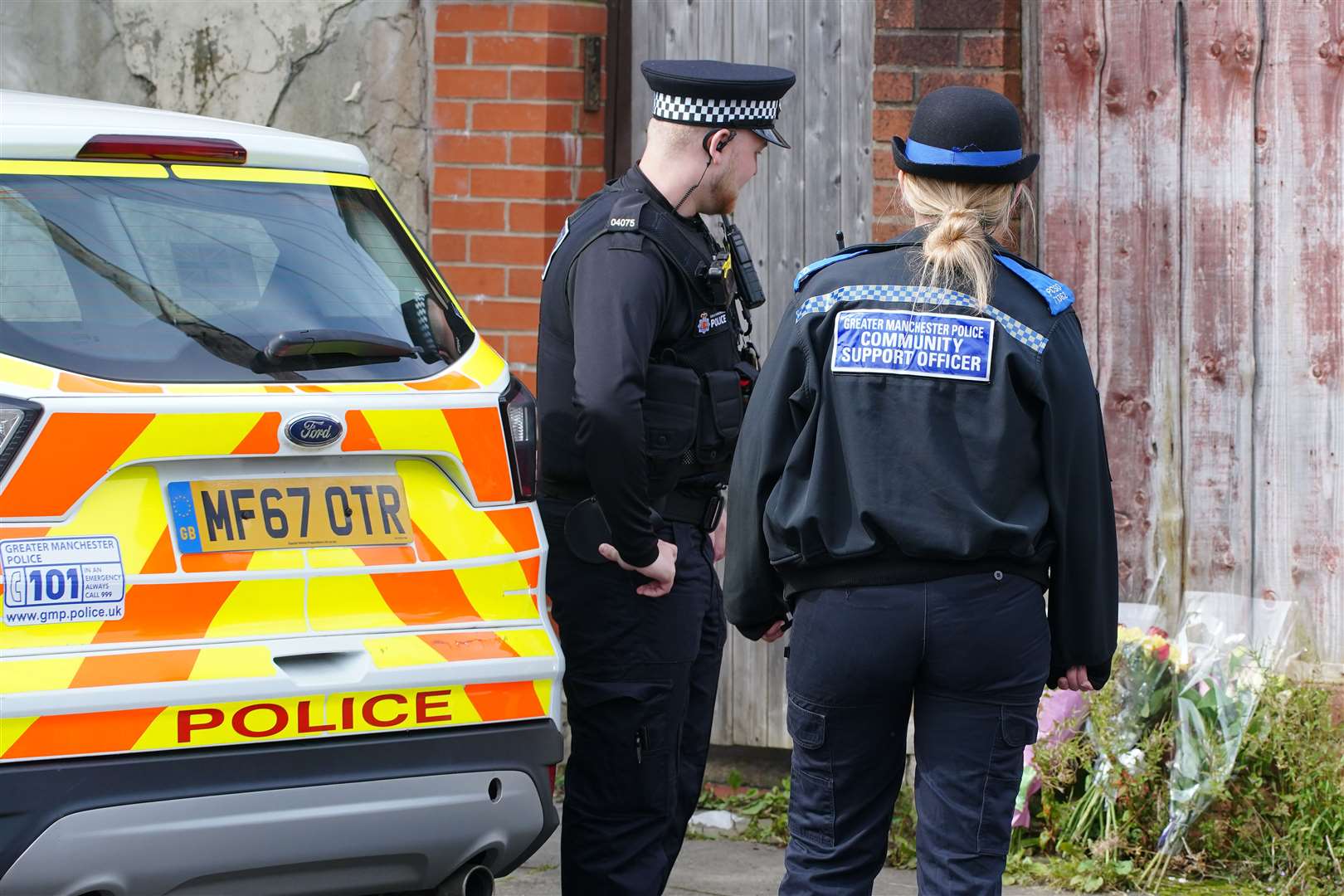 Police officers looking at flowers left outside Mr Patience’s property in Radcliffe, Greater Manchester (Peter Byrne/PA)