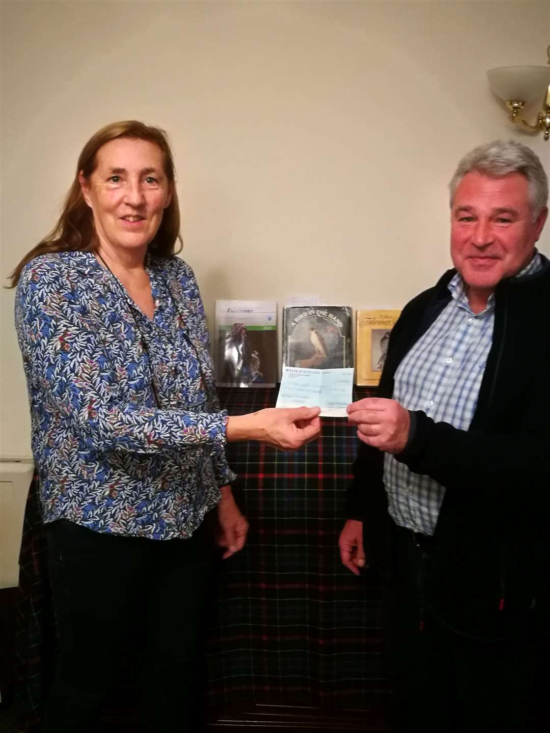 Elizabeth Sweetman, president of the Rotary Club of East Sutherland, presents a £900 cheque to falconer Andy Bunting.