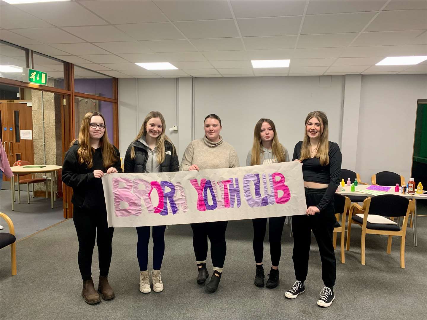 Youth worker Megan Penny (centre) and three of the young people who attend the club hold up a banner they created.