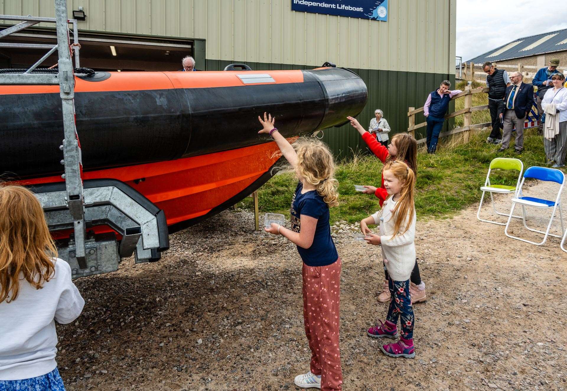 Children at the ceremony were invited to sprinkle holy water over the new lifeboat and crew members. Picture: Andy Kirby