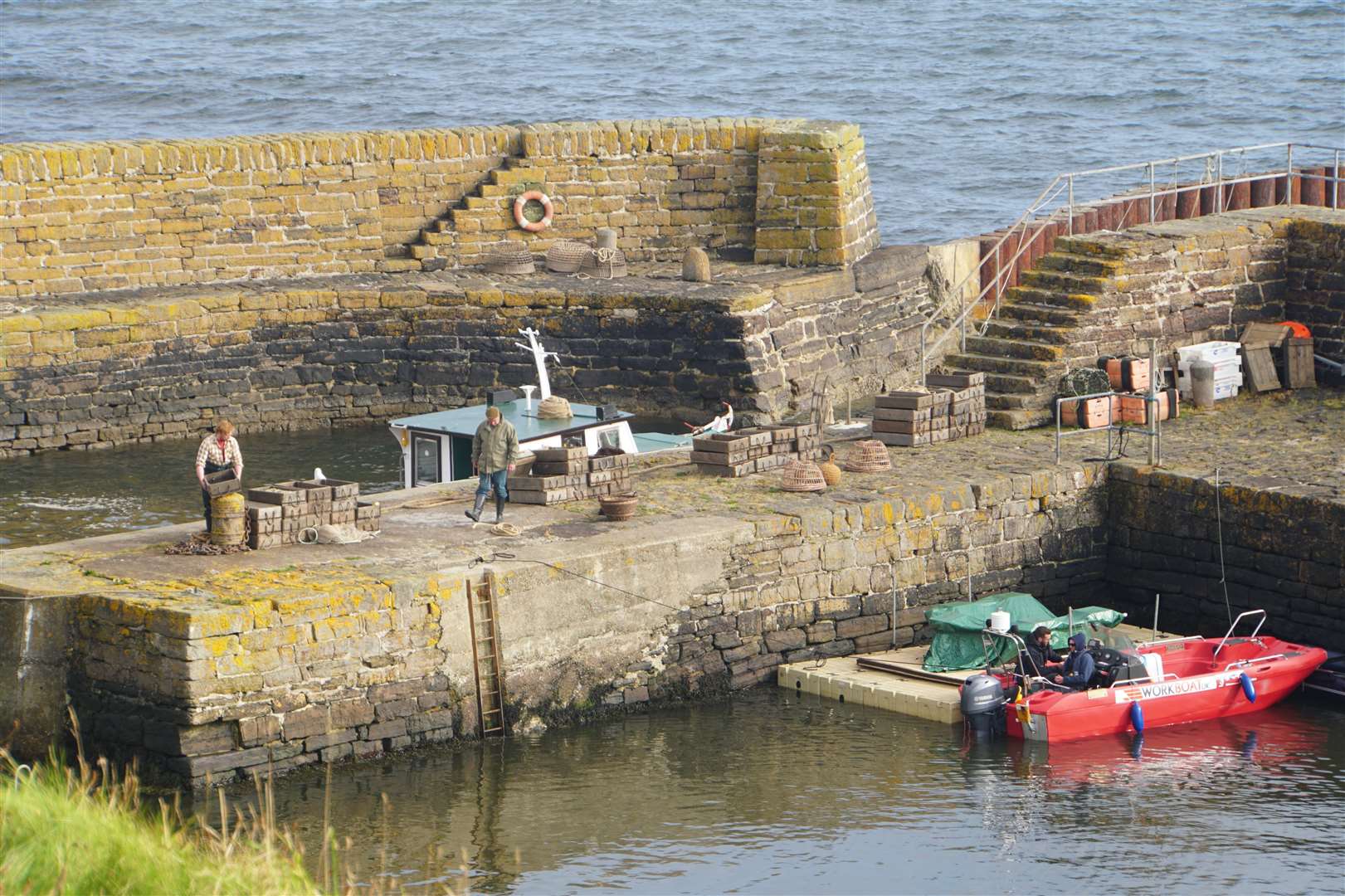 Actors at Keiss harbour for The Crown film shoot in 2019. The pontoon beside the red boat was used to stage a special effect with an explosion. Picture: DGS