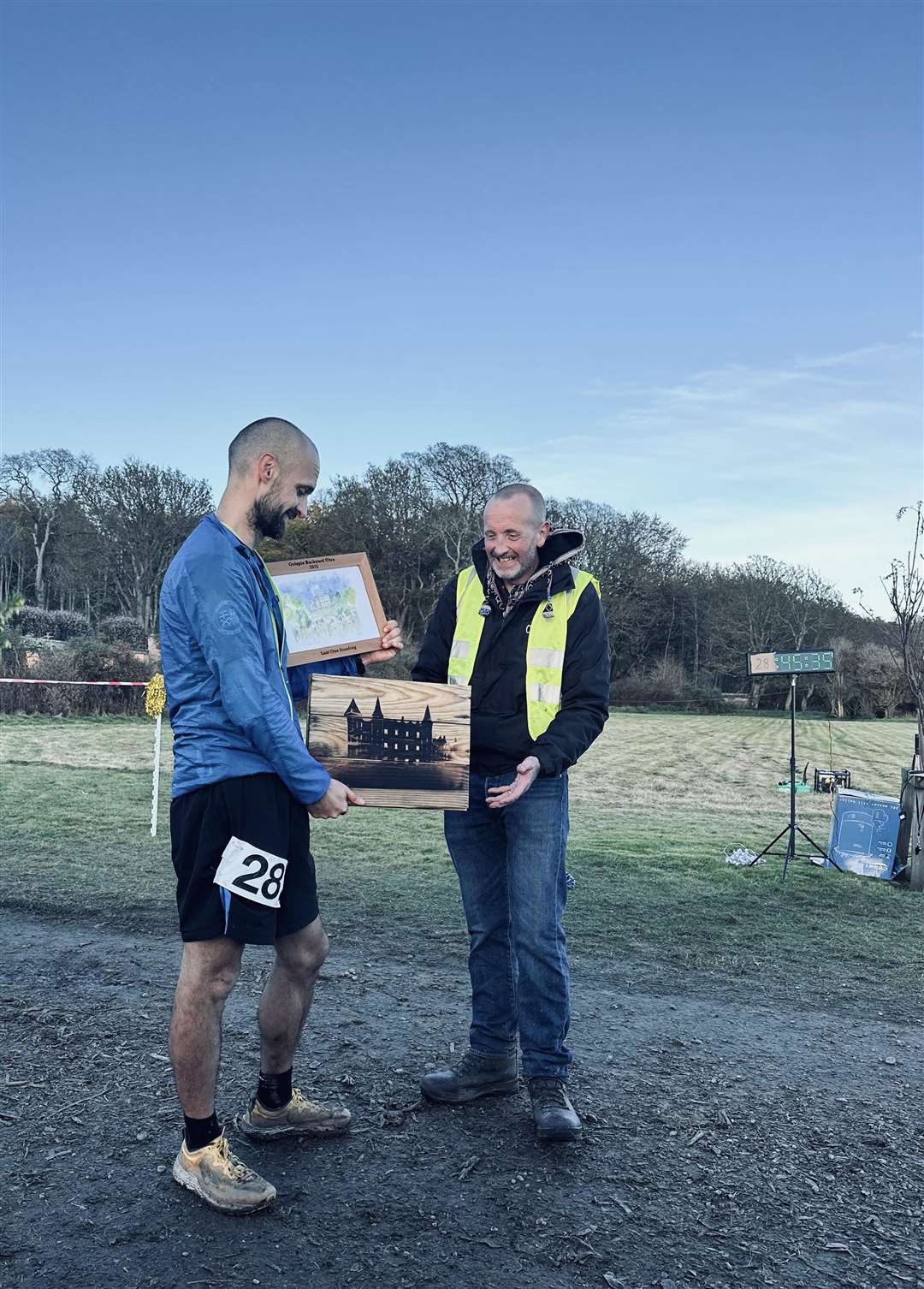 Golspie Backyard Ultra winner Mike Raffan is presented with a bespoke watercolour of Dunrobin Castle by race organiser Ian Harrison.