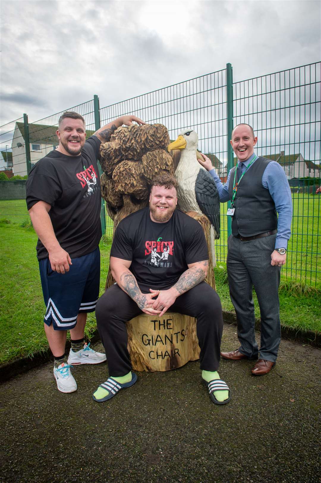 Tom and Luke Stoltman were surprised by school children at South Lodge with a specially made Giants Chair Bench thanks to a donation they made to the school.  They are pictured with director David Hayes-MacLeod.  Photo: Callum Mackay