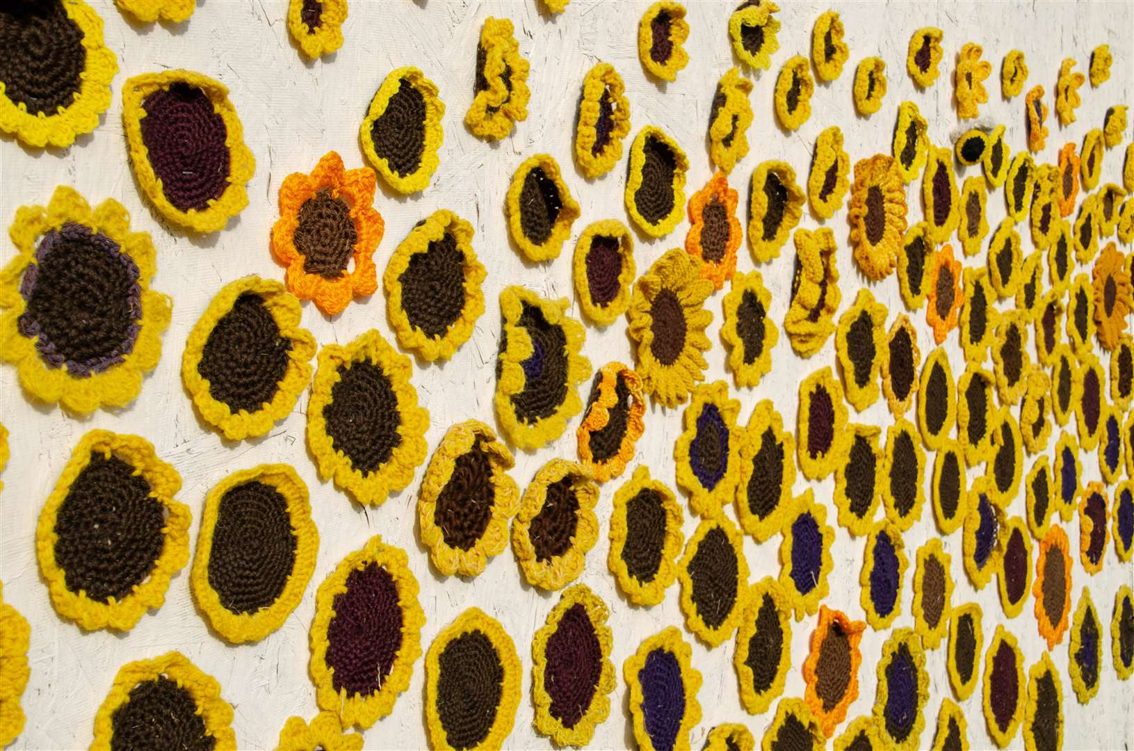 A wall of cheerful, handmade crochet sunflowers.