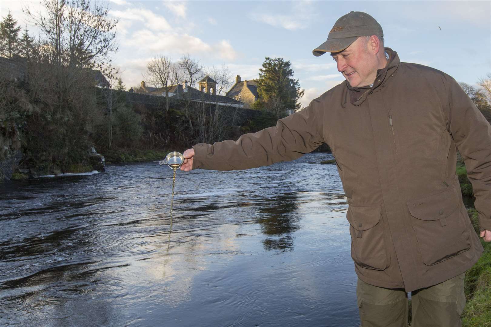 John Drummond, estate manager for Thurso River Ltd, pours a quaich of whisky into the water to toast the opening of the 2023 salmon season. Picture: Robert MacDonald / Northern Studios