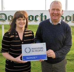 Royal Dornoch Golf Club captain Hamish Macrae receives the Investors in People Scotland award from consultant Ruth Oulton.