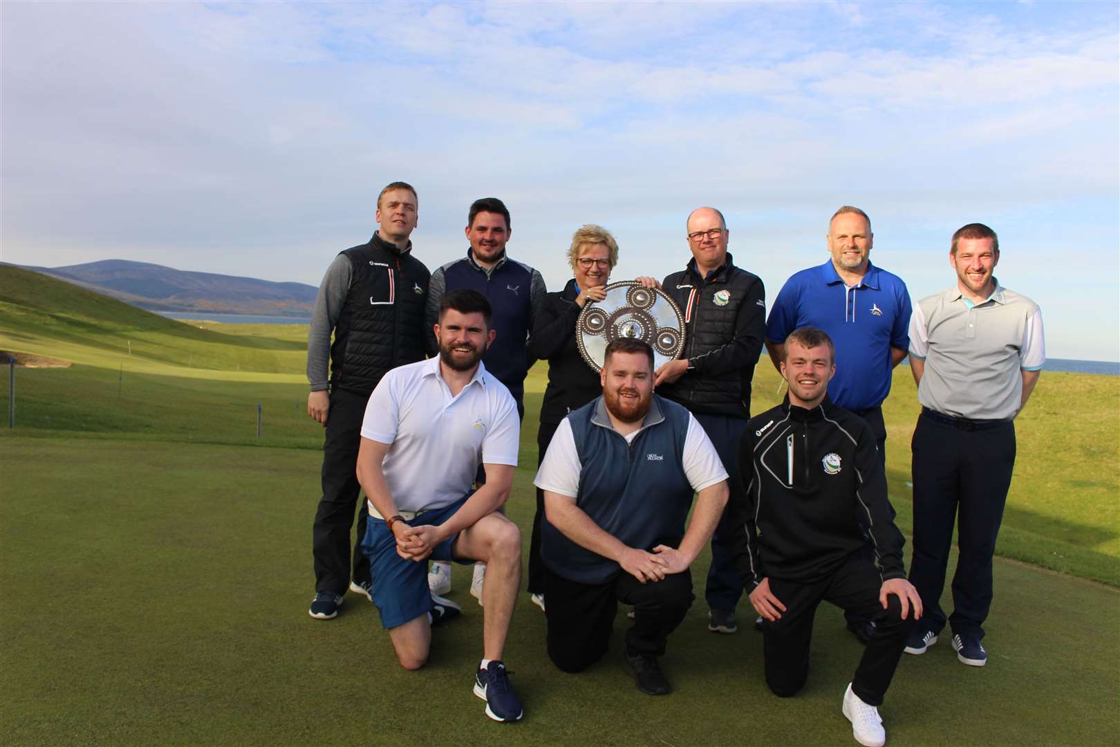 Brora club captain Anne Clarke presents team captain Roddy Cameron with the targe, along with team mates Graham Grant, Alistair MacDonald, James MacBeath, and Dougie Thorburn. Front – Calum Stewart, Owen MacLennan and Stuart Murray.