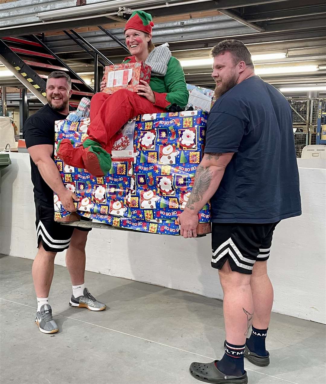 Tom and Luke Stoltman raise a pallet of shoe boxes with Shona Mackenzie, one of Blythswood’s sorting team, seated atop.