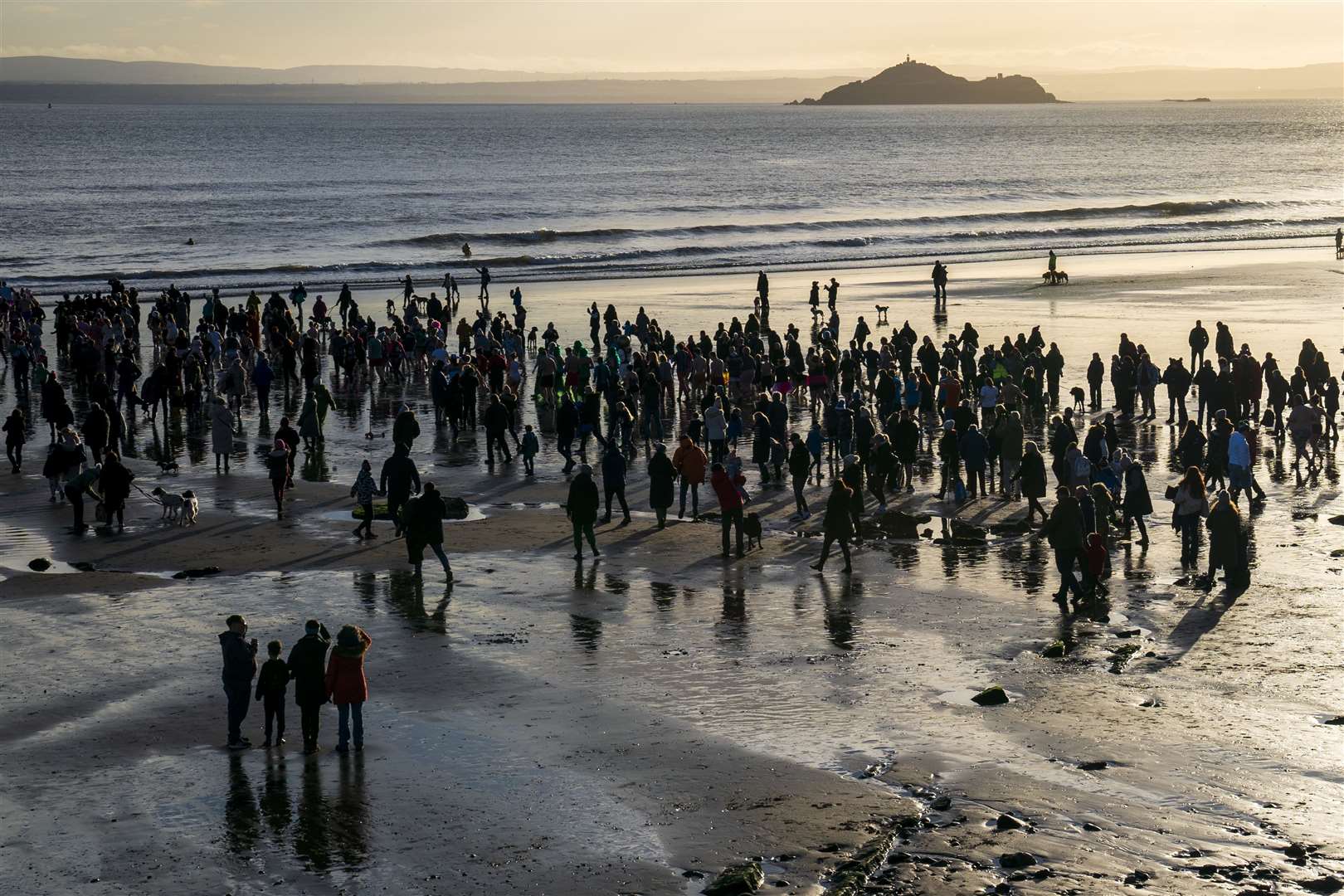People gather on the beach to watch the Loony Dook New Year’s Day dip in the Firth of Forth at Kinghorn (Jane Barlow/PA)
