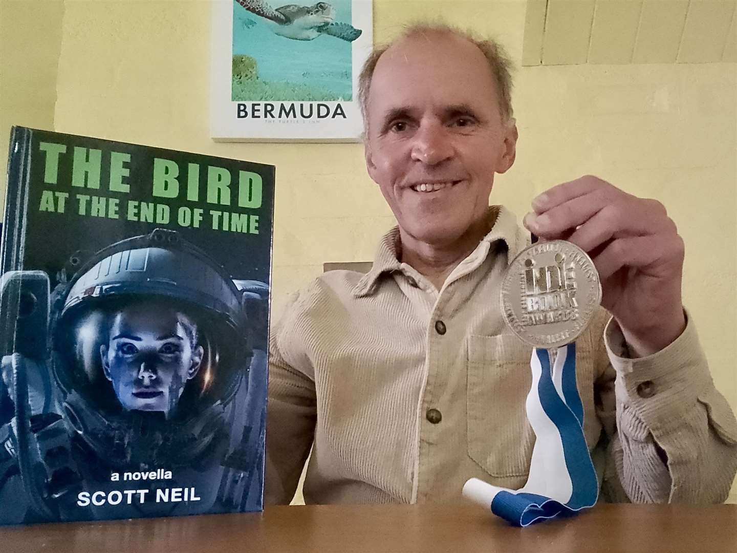 Scott Neil, with his novella The Bird At The End Of Time and awards finalist medal.