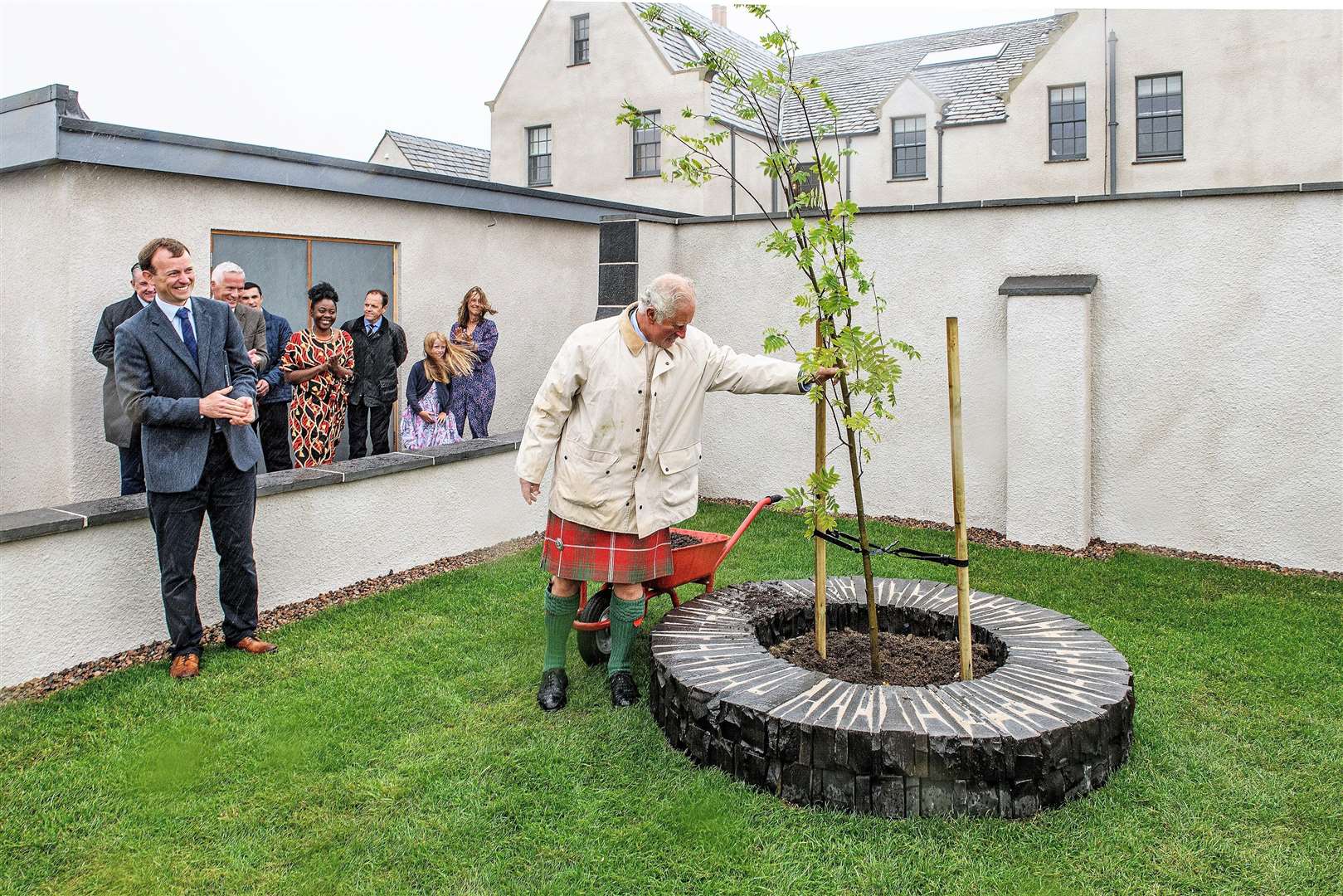 A round of applause for the prince as he braves the elements to plant a commemorative tree in the gardens. Picture: Angus Mackay