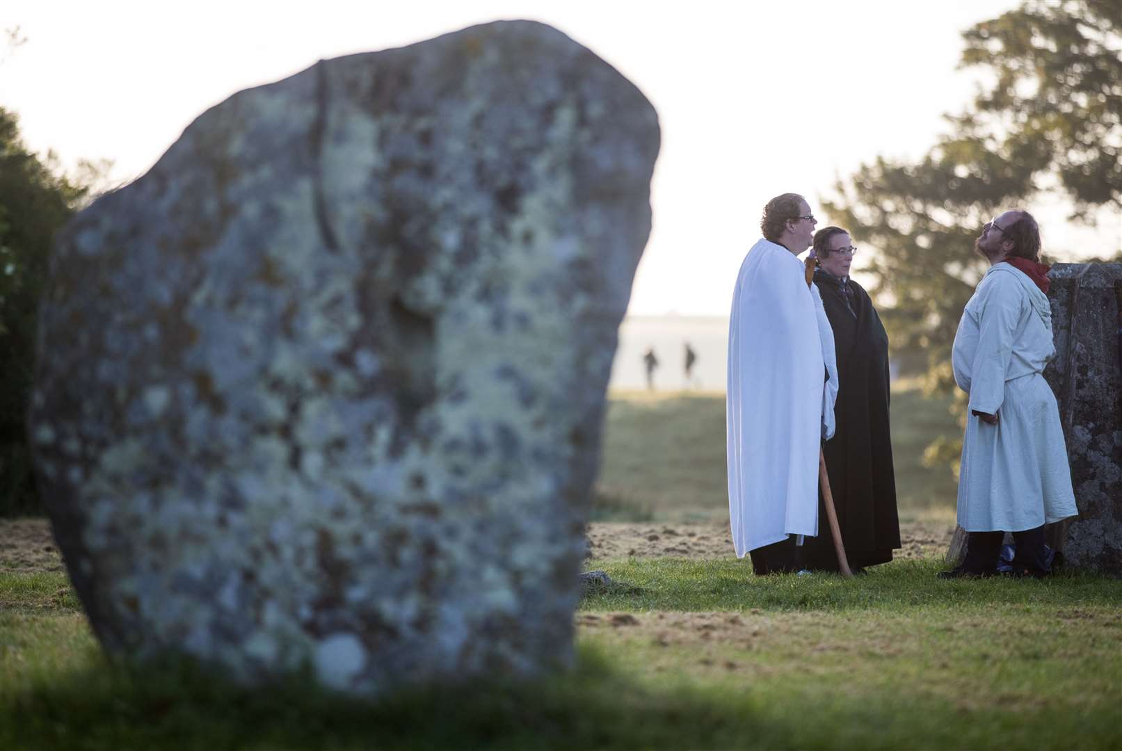 People gather around stones at the Avebury stone circle in Wiltshire, where they celebrated the dawn of the longest day in the UK in 2019 (Andrew Matthews/PA)